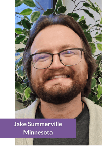Portrait of a smiling person with glasses and a beard against a background of leafy plants.