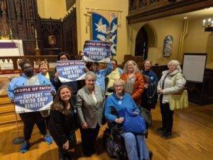 A group of people holding signs supporting food assistance inside a church setting.